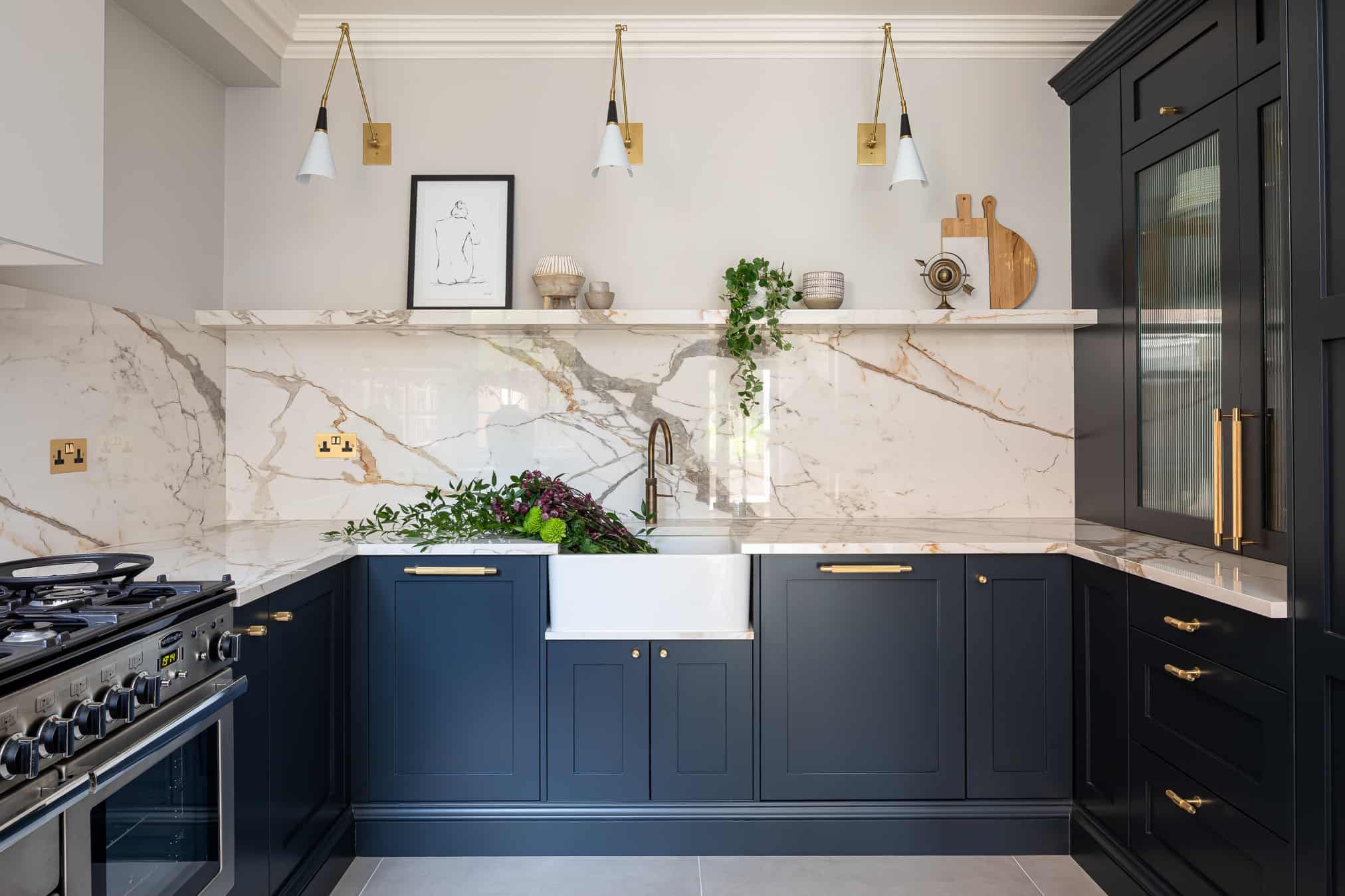 John Lewis of Hungerford luxury Shaker kitchen with blue cabinetry and gold handles with marble worktops and marble splashback
